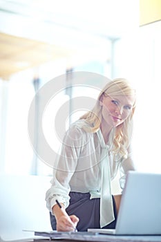 Shes got the corporate edge. Portrait of a beautiful business woman sitting on her desk and writing notes from her