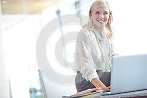 Shes got good work ethic. Portrait of a smiling business woman sitting at her desk with a laptop in front of her with