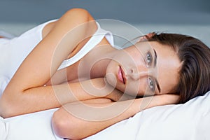 Shes got a lot on her mind. A young woman looking sad while lying on her bed.