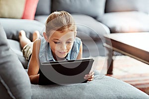 Shes got a whole library of ebooks saved online. a little girl using a digital tablet at home.