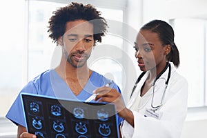 Shes great at explaining the scans. a female African American doctor and male nurse studying a CAT scan.