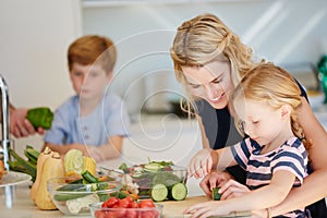 Shes a great little chef. Cropped shot of a mother cooking together with her two kids at home.