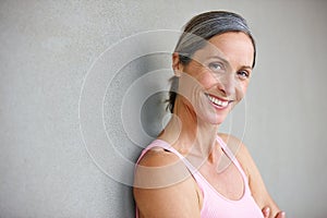 Shes in great shape. Portrait of an attractive mature woman in gymwear leaning against a gray wall.