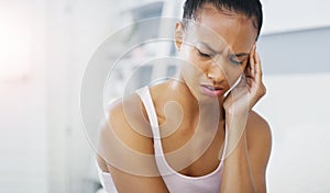 Shes having an awful start to the day. an attractive young woman suffering from a headache in her bedroom at home.