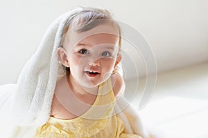 Shes always laughing. a cute little baby girl sitting on the floor playing with her blanket.