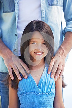 Shes my special little girl. Portrait of a smiling little girl with her father standing behind her.