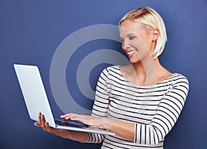 Shes new to the blogosphere. Studio shot of an attractive young woman using a laptop.