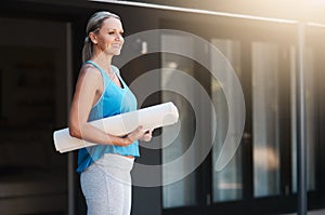 Shes ready for her morning yoga session. a mature woman smiling and holding her yoga mat outside of her home in the