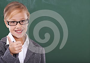 Shes ready to learn. Portrait of a little girl pretending to be a teacher and showing a thumbs up.