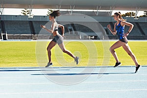 shes setting the pace. Full length shot of two attractive young female athletes running along the track.