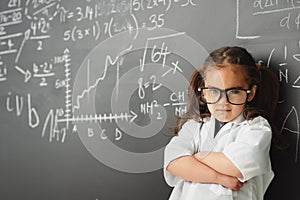 Shes a smarty pants. a young girl with a blackboard full of math equations.