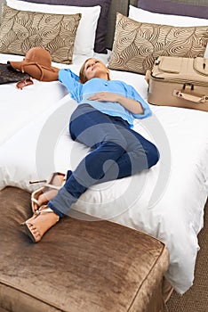 Shes taking some time to relax. an young woman relaxing on her hotel room bed.