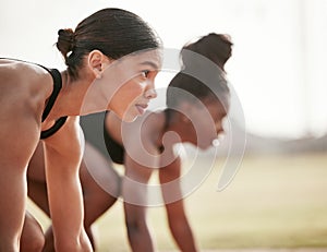 Shes only thinking about winning. two attractive young female athletes starting their race on a track.