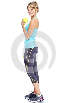 Shes toning up and feeling fit. Attractive young woman in sportswear lifting dumbbells while isolated on white.