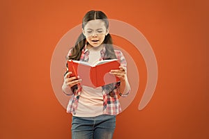 Shes a true bookworm. Adorable small child reading book on orange background. Cute little girl reading for fun