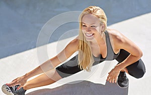 Shes unbelievably flexible. Full length shot of a young woman stretching her legs outside.