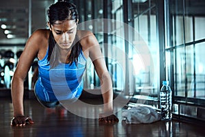 Shes a warrior. an attractive young woman doing pushups as part of her workout in the gym.