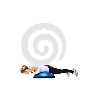 Shes working on her abs. A young woman working her core on a bosu-ball.