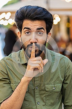 Indian man presses finger to lips makes silence hush sign do not tells gossip secret quiet in city