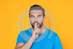 Shh man. Portrait of man showing shh taboo sign with finger to lips over yellow studio background. The secret. Hush shut