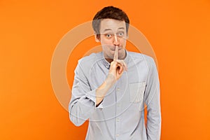 Shh, it`s secret! Businessman holding finger near mouth and look