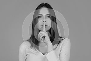 Shh, womens secrets. Woman showing secret sign. Female with finger in mouth. Closeup portrait of young woman is showing
