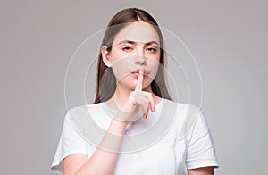 Shh, womens secrets. Woman showing secret sign. Female with finger in mouth. Closeup portrait of young woman is showing