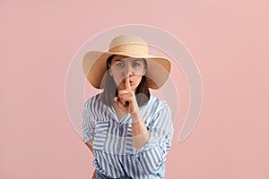 Shhh. Brunette woman holds forefinger near lips in silence gesture, ask for quietness for repose on vacation, wears photo