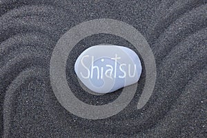 Shiatsu word carved on a stone over black volcanic sand