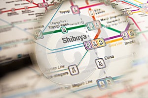 Shibuya Tokyo metro station on a printed metro map under a magnifier lens