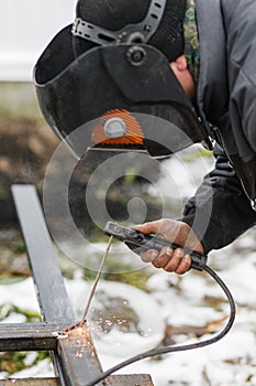 Shielded metal arc welding. Worker welding metal with electrodes, wearing protective helmet and gloves. Close up of electrode