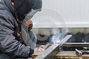 Shielded metal arc welding. Worker welding metal with electrodes, wearing protective helmet and gloves. Close up of electrode