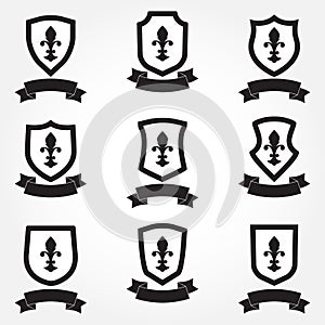 Shields icon set. Different shield shapes with fleur-de-lis symbol and stylish ribbon. Heraldic royal design. Vector illustration