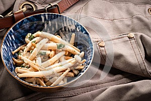 Shimeji mushrooms in a bowl on grey chef`s apron background. Pickled japanese brown beech or buna shimeji. Umami taste