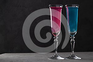 Shimmer edible glitter sparkling pink and blue wine in two tall glasses on dark gray background. Copy space