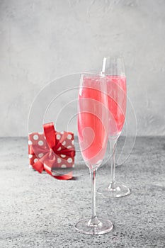 Shimmer edible glitter sparkling wine in two glasses with gift on grey.