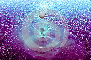 Shimmery Purple and Blue Water with A Milky White Droplet in Motion
