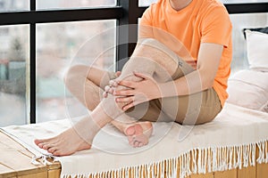 Shin pain, man suffering from ache and doing self-massage at home