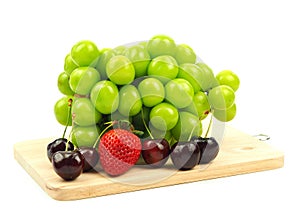 Shine Muscat grape, strawberry and cherry on cutting board isolated on a white background.
