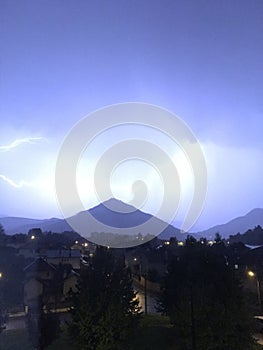 Shine and thunderstorm above mountain and city