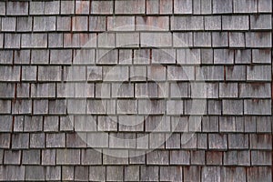 Shingle wooden tile facade background.Texture of old weathered wooden tiled  roof or surface of natural  veneer wall backdrop. Eco