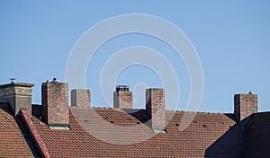 Shingles rooft with chimneys against the clear blue sky