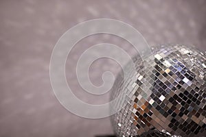 Shining disco ball on grey background close-up.