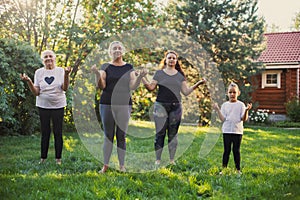 Shining females four generations of family doing yoga meditating with their hands raised and fingers connected standing