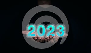 Shining and glow blue 2023 year calendar. The 2023 numbers on the businessman`s hands on dark background.