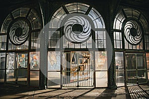 Shining metal gate stands illuminated in the evening light, a window visible in the background