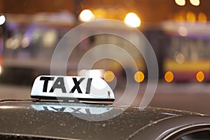 Shining Taxi inscription close up against passing cars on night street of big cit