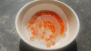 Shining, transparent, orange color crystal beads or gemstones in a bowl