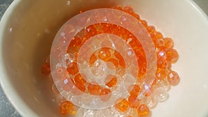Shining, transparent, orange color crystal beads or gemstones in a bowl