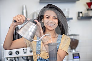 Shining young woman pouring water into airpress